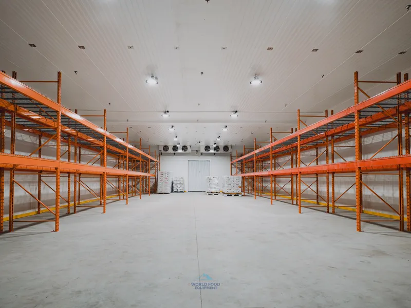 Cathedral-scale finished walk-in cooler at Halal Meats with dual orange pallet racking on both sides, ceiling-mounted KeepRite evaporators visible at the far end, World Food Equipment install, Ontario